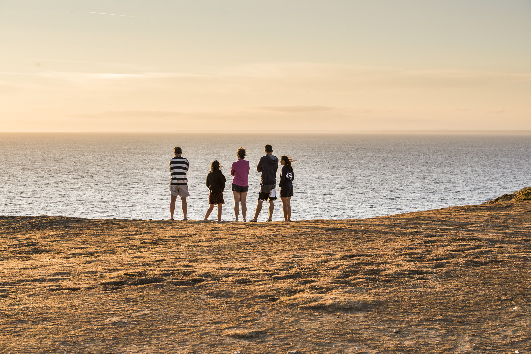 Grupo de personas viendo la puesta de sol en Pen Men, isla de Groix (Bretaña, Francia)